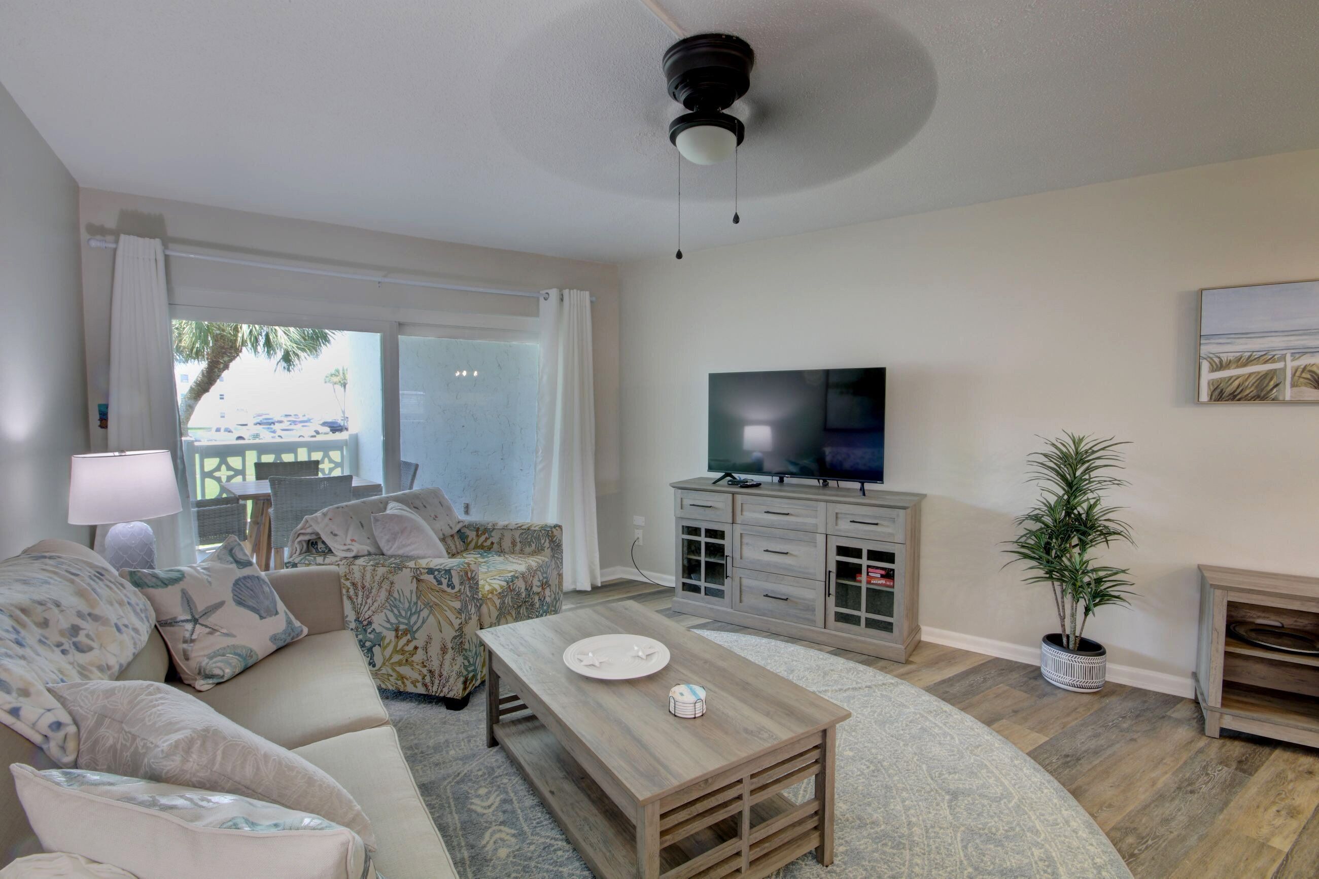 Una sala de estar con sofá, mesa de centro, televisor y una planta en maceta.