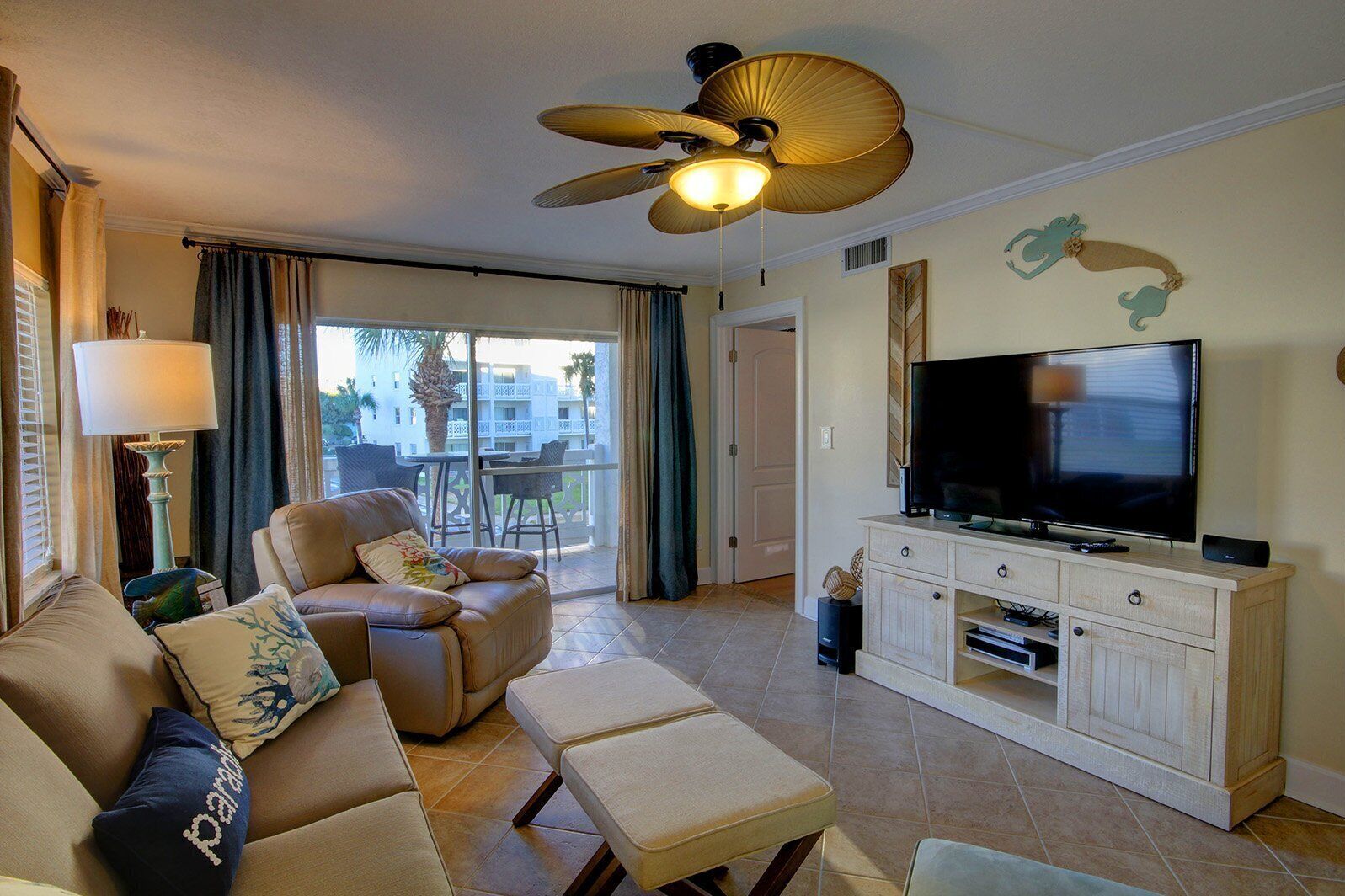 A living room with a sofa, armchairs, a television, and a ceiling fan.