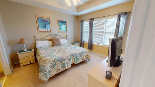 A bedroom with a bed, nightstands, a TV, and artwork on the wall. - Ironwood 1233 (North Myrtle Beach)