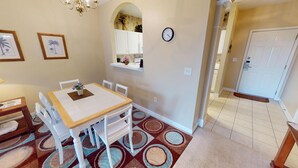 A dining area with a table and chairs, a chandelier, framed botanical prints, and a clock on the wall. - Ironwood 1233 (North Myrtle Beach)