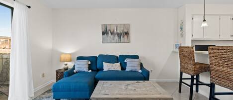 Ein modernes Wohnzimmer mit einem blauen Modulsessel, einem Holztisch und einem Deckenventilator.
