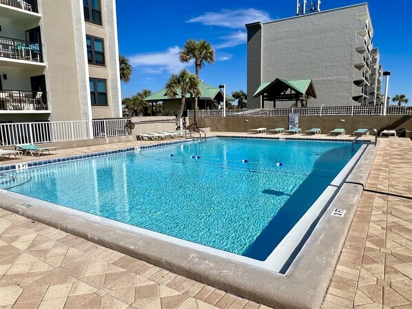 A rectangular swimming pool with clear blue water, surrounded by a tiled deck. - Emerald Isle 102 - The Seashell (Fort Walton Beach)