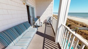 A balcony with a striped sofa, two chairs, and a small table. - Atlantis Villas 205 (North Myrtle Beach)