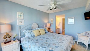 A bedroom with a bed, nightstands, a chair, a ceiling fan, and a television. - 446 El Matador (Fort Walton Beach)