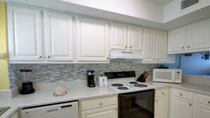 A kitchen with white cabinets, a dishwasher, a stove, a microwave, and a coffee maker. - 446 El Matador (Fort Walton Beach)