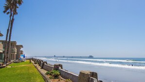 A coastal view with a beach, a pier, and a building with a balcony overlooking the ocean. - North Coast Village B212 (Oceanside)