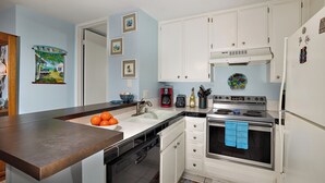 A kitchen with white cabinets, a stainless steel stove, and a dishwasher. - North Coast Village B212 (Oceanside)
