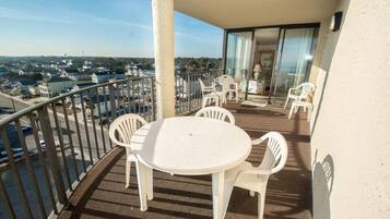 A balcony with a round table and four chairs, overlooking a residential area.