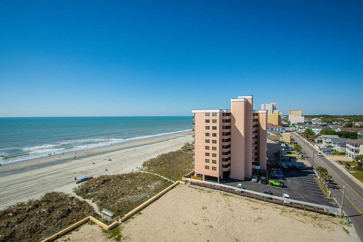 A beachfront hotel with multiple buildings, a sandy beach, and the ocean.