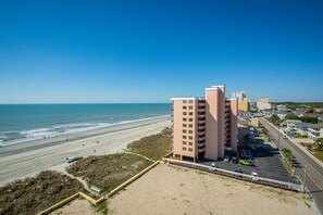 A beachfront hotel with multiple buildings, a sandy beach, and the ocean. - Sea Castle 8G (North Myrtle Beach)
