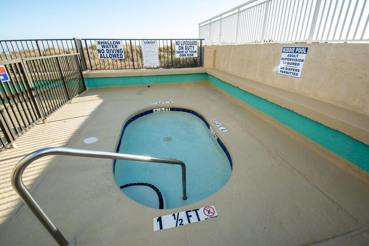 A kiddie pool with a shallow water warning, no diving allowed, and a lifeguard duty sign.