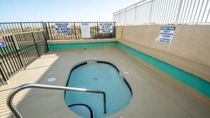 Une petite piscine pour enfants avec un panneau indiquant une faible profondeur, interdisant la plongée et précisant qu’il n’y a pas de sauveteur.