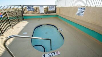A kiddie pool with a shallow water warning, no diving allowed, and a lifeguard duty sign.