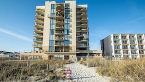 Un hôtel situé en bord de mer, doté de nombreux balcons, avec une plage de sable devant et un panneau indiquant qu’il s’agit d’une propriété privée.