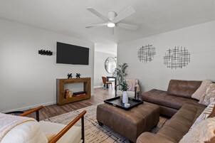 A modern living room with a brown leather sofa, a wooden coffee table, and a flat-screen TV mounted on the wall.