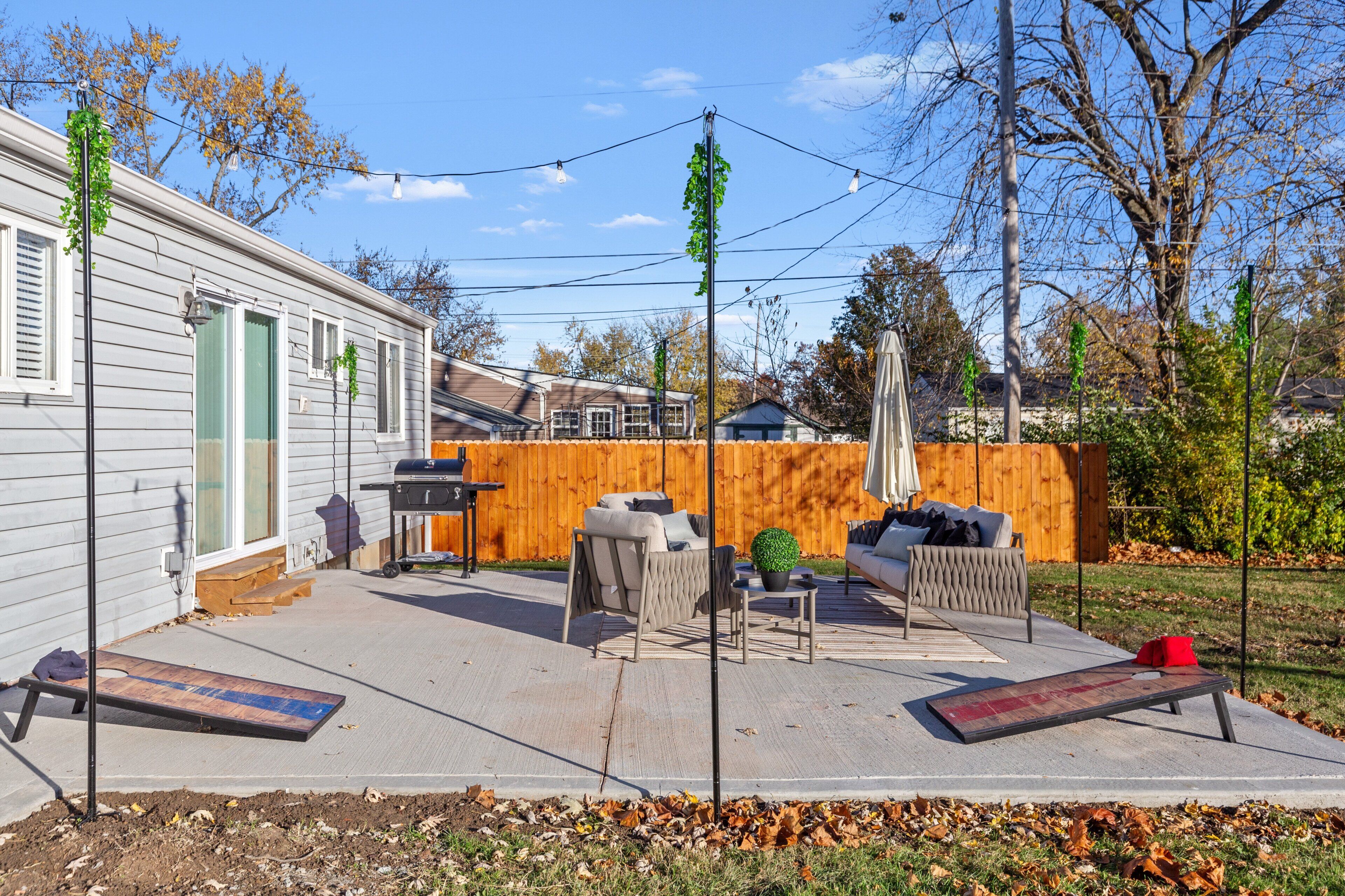 A patio area with outdoor furniture, a barbecue grill, and a wooden fence.