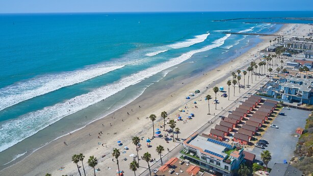 A coastal hotel with a beach view, rows of rooms, and a parking area. - Oceanview Beach Home - 209w (Oceanside)
