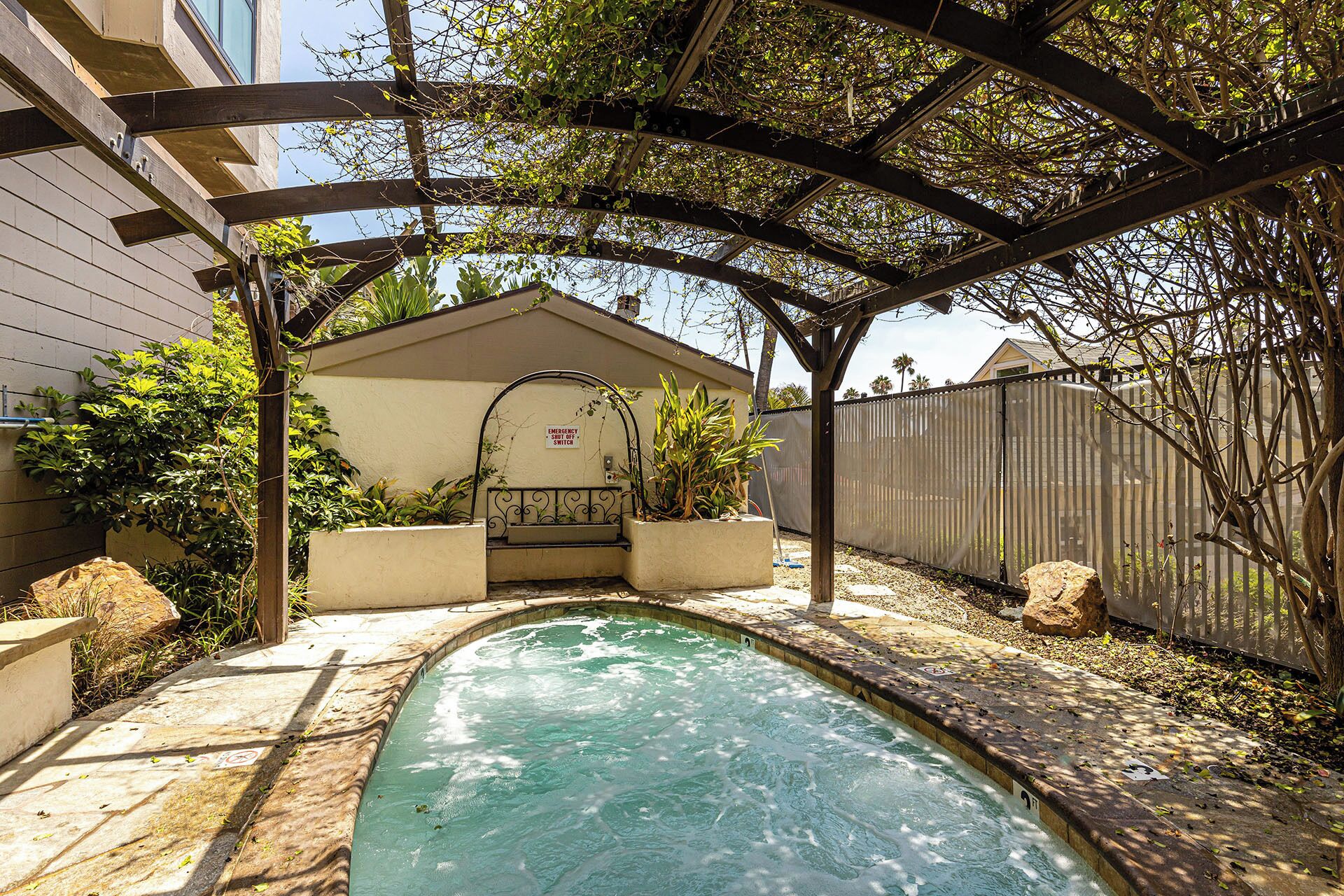 A backyard with a swimming pool, a pergola, and a house.
