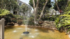 Une fontaine dans un jardin, avec un bâtiment en arrière-plan.
