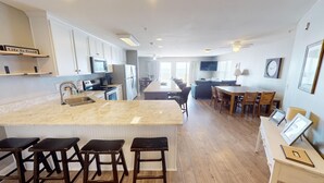 Una cocina moderna con una isla grande, taburetes de bar y un comedor con mesa y sillas.