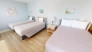 Habitación de hotel con dos camas individuales, una mesita de noche con lámpara y suelo de madera.