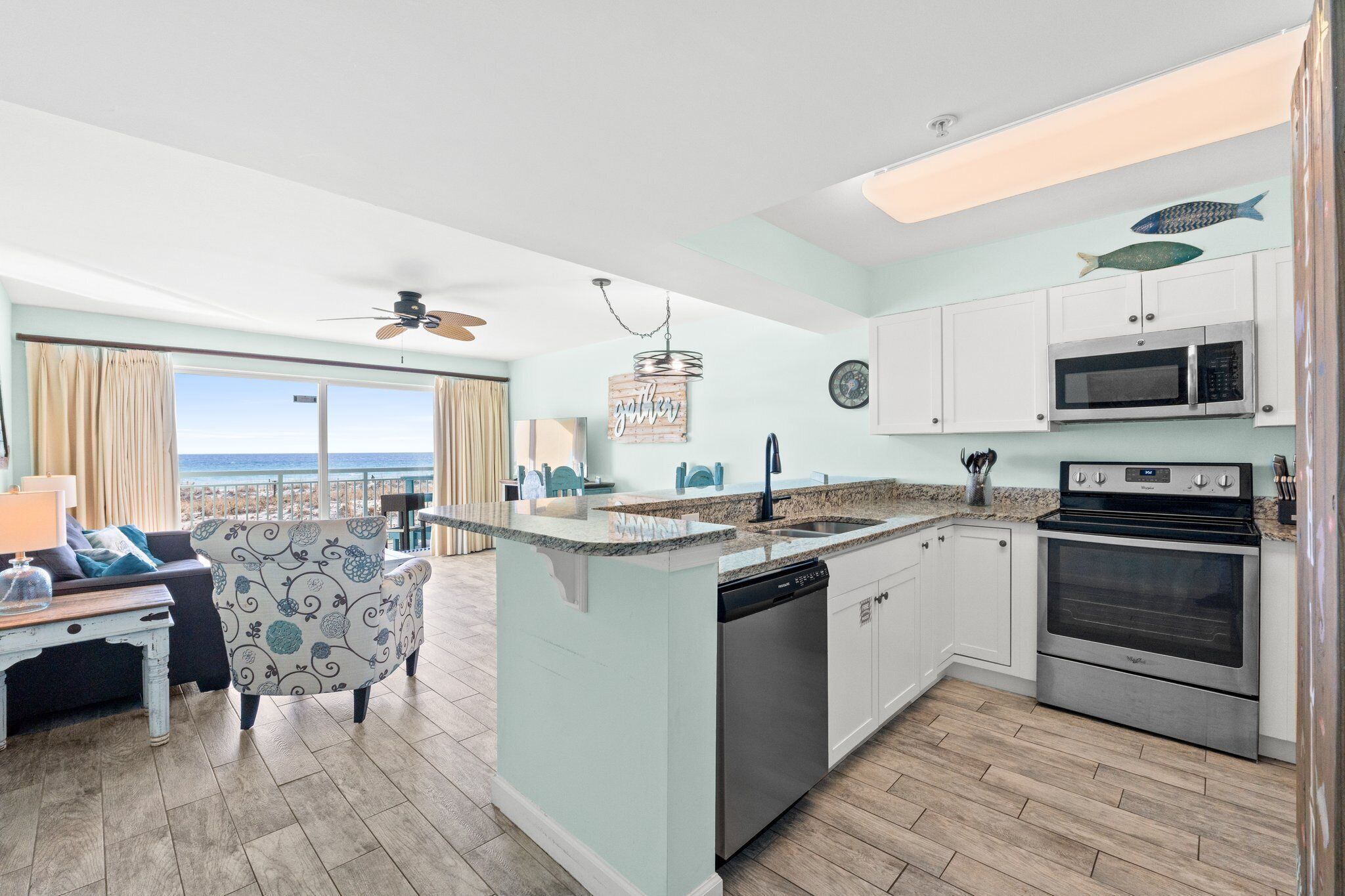 A kitchen with a view of the ocean, a dining area with a view, and a ceiling fan.