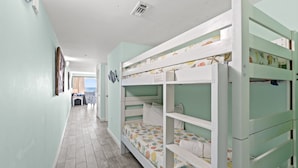 A corridor with bunk beds, a small table, and a view of the sea. - Pelican Isle 113 - Salty Seahorse (Fort Walton Beach)