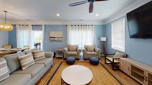 Un salon comprenant un canapé, des fauteuils, une table basse, un téléviseur et un ventilateur de plafond.