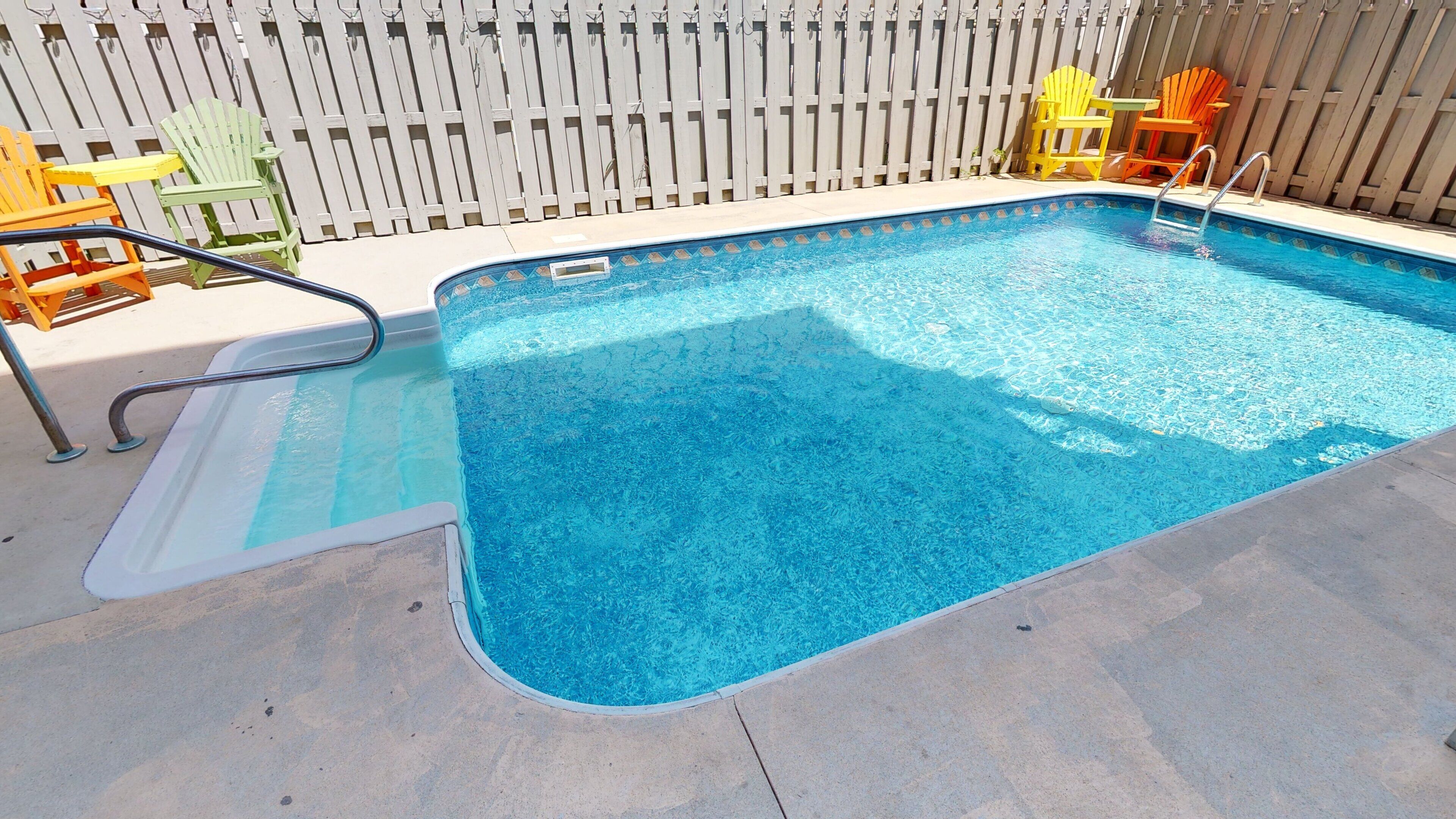 A rectangular swimming pool with a clear blue water surface, surrounded by a concrete deck.