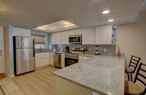 A modern kitchen with stainless steel appliances, white cabinetry, and a granite countertop. - 366 El Matador (Fort Walton Beach)