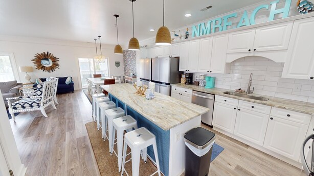 A modern kitchen with white cabinets, a marble countertop, and a built-in dishwasher. - Bermuda Breeze - A (North Myrtle Beach)