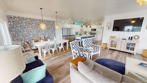 Ein modernes Wohnzimmer mit Essbereich, Küche und einem an der Wand befestigten Fernseher.