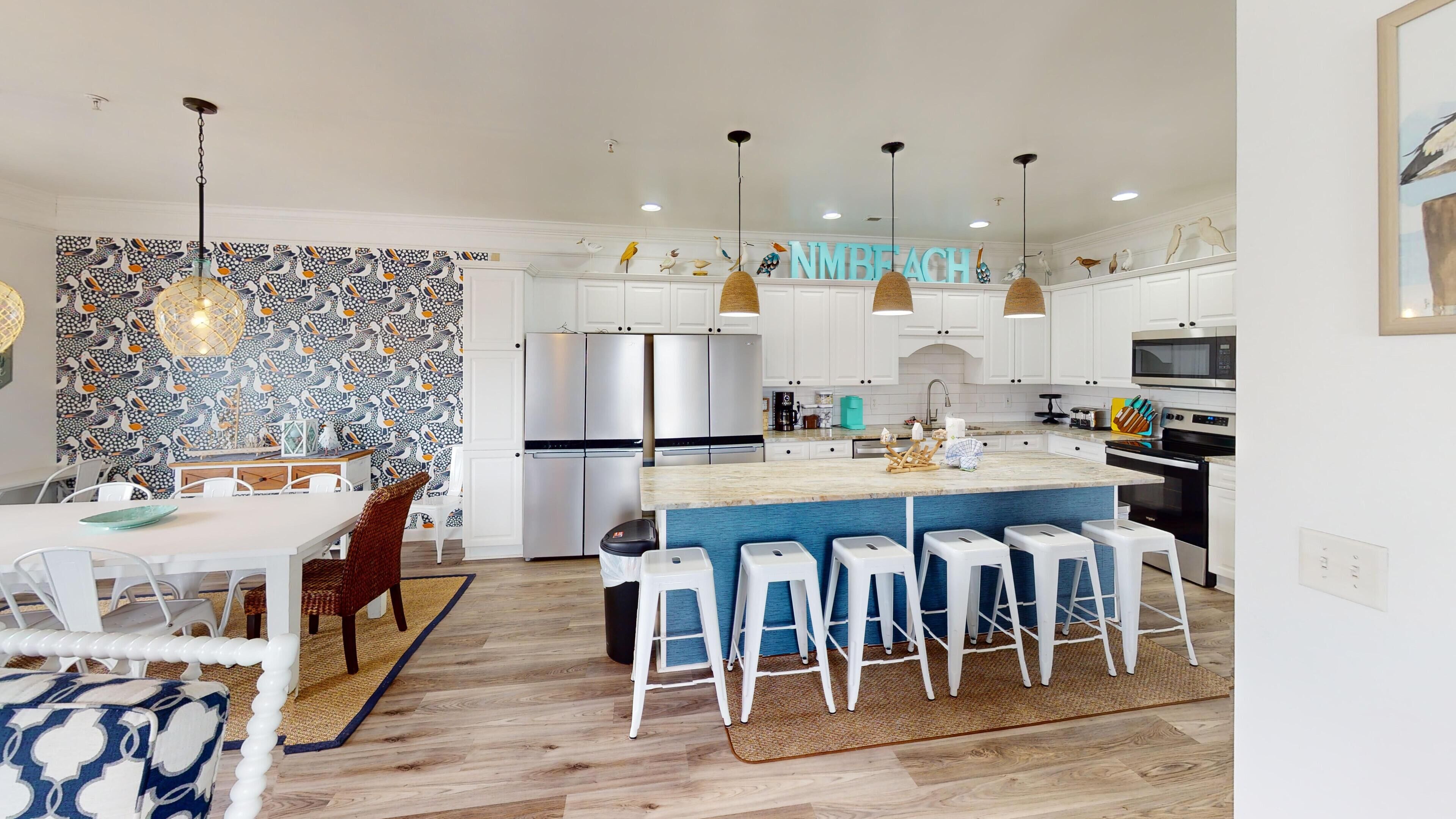 Una cocina moderna con gabinetes blancos, electrodomésticos de acero inoxidable y una isla azul con taburetes de bar.