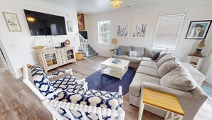 A living room with a sofa, a coffee table, a TV, and a staircase. - Bermuda Breeze - A (North Myrtle Beach)