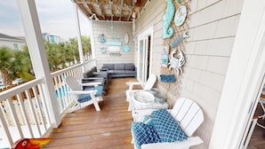 A covered outdoor area with white wooden furniture, including chairs and a sofa, arranged around a small table. - Bermuda Breeze - A (North Myrtle Beach)