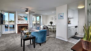 A spacious living room with a fireplace, a dining area, and a kitchen. - North Coast Village Cottage G20 (Oceanside)