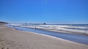 A beach with a pier extending into the ocean, sandy shore, and clear blue sky. - North Coast Village Cottage G20 (Oceanside)