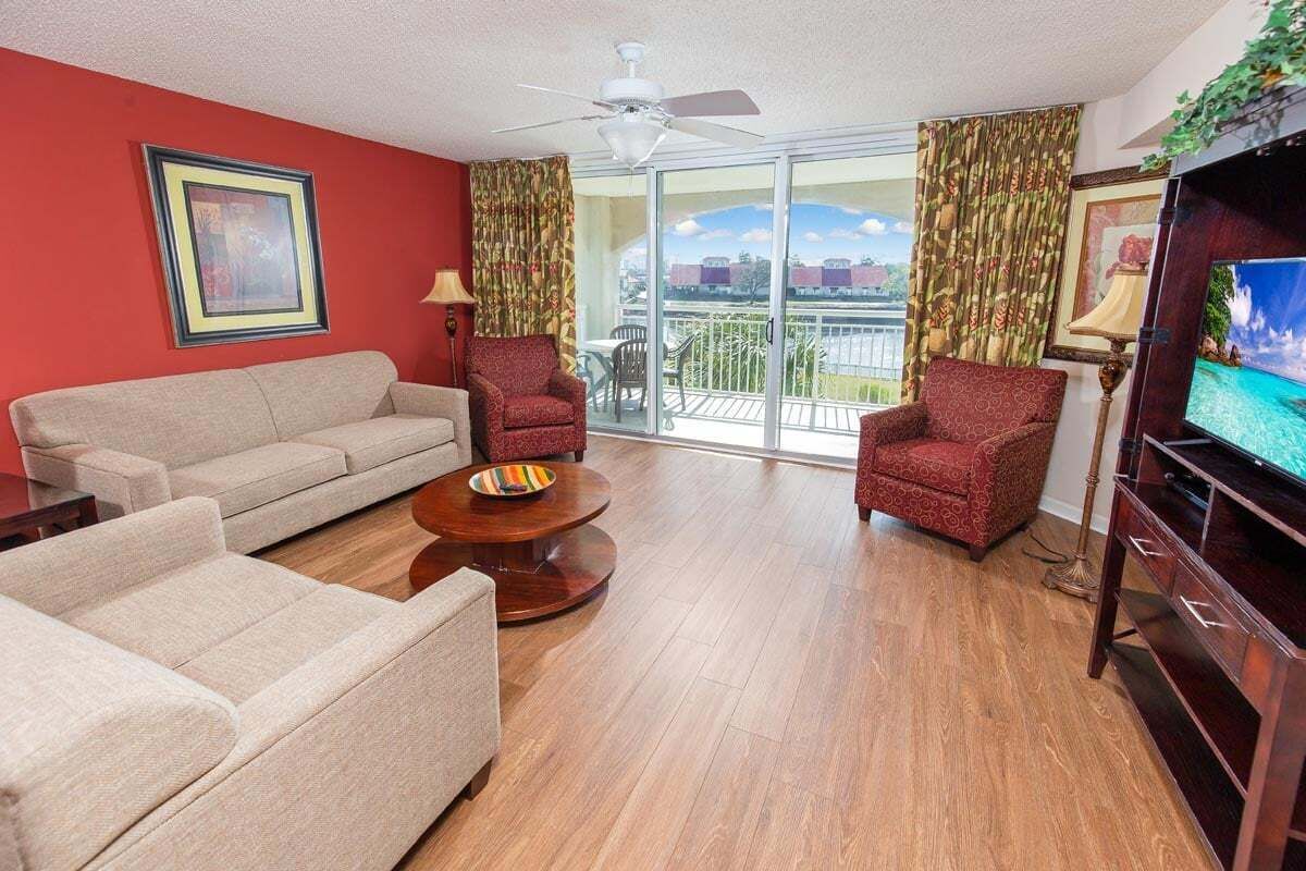 A living room with a sofa, two armchairs, a coffee table, and a TV.