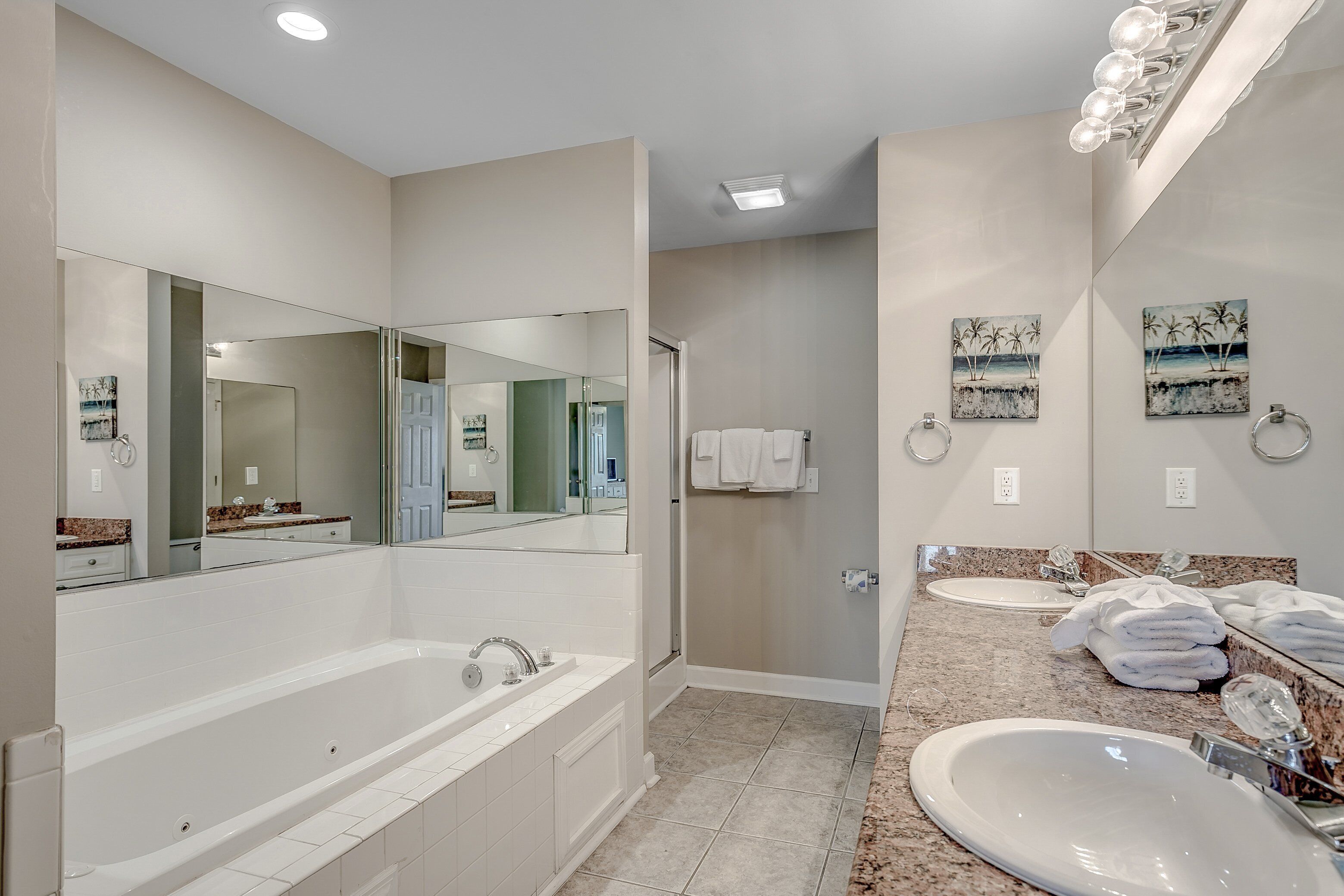 Un baño moderno con una bañera grande, dos lavamanos y una ducha a ras de suelo.