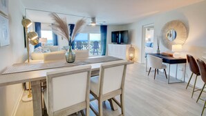 Una sala de estar moderna con comedor, ventanas grandes y vistas a la ciudad.