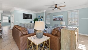 Un salon avec un canapé en cuir marron, une table basse en bois et un ventilateur de plafond.