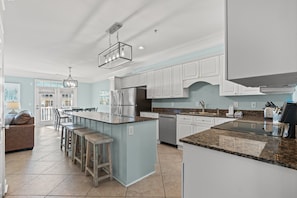 A modern kitchen with white cabinets, a granite countertop, and stainless steel appliances. - Grand Cayman Villas - I (North Myrtle Beach)