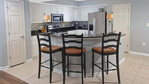 A kitchen with a central island, white cabinets, and a microwave. - Yacht Club 2-404 (North Myrtle Beach)