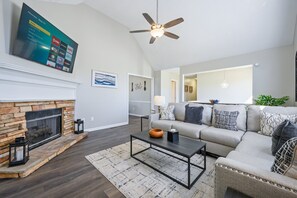 A living room with a fireplace, a sofa, a coffee table, and a TV mounted on the wall. - 126 Manning Mill Adairsville (Adairsville)