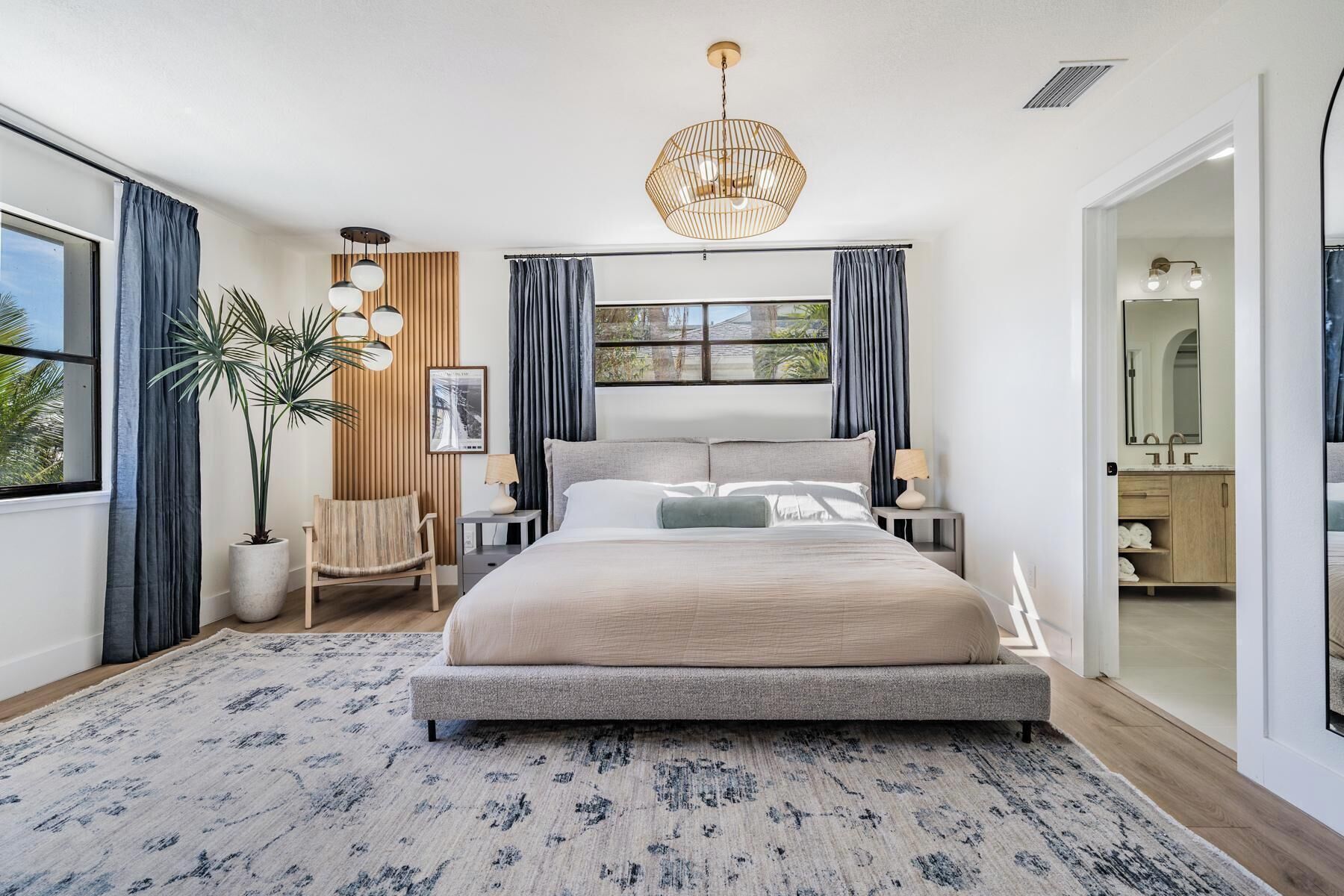 Un dormitorio moderno con una cama grande, una lámpara colgante, una planta en maceta y vistas al exterior.