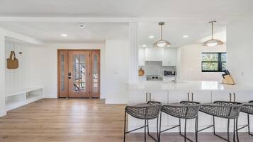 A modern kitchen with white cabinets, a central island, and bar stools.