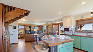 A kitchen with wooden flooring, a central island, and a staircase. - Lindas Perch (Ashton)