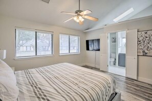 Ein Schlafzimmer mit Bett, Deckenventilator, Fernseher und Schrank mit Schiebetür.