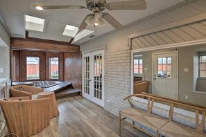 Ein geräumiges Zimmer mit einem großen Deckenventilator, einer Whirlwanne, Korbmöbeln und Blick ins Freie.