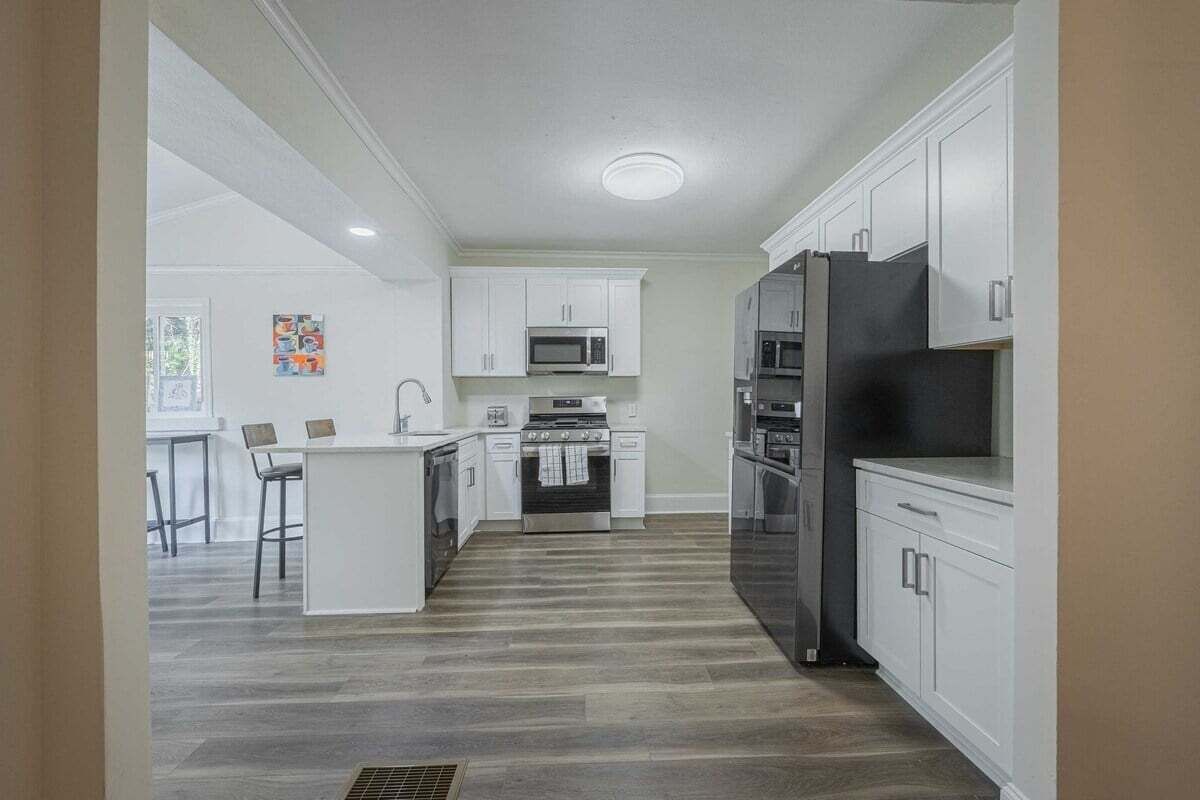 Une cuisine moderne avec des meubles blancs, des appareils en acier inoxydable et un îlot central.